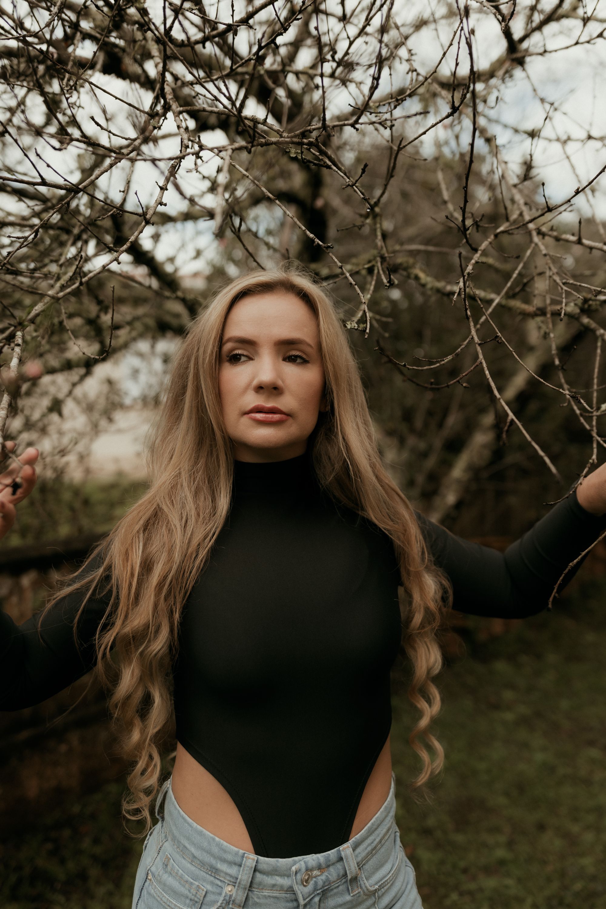 Kobieta z długimi naturalnymi włosami w sadzie